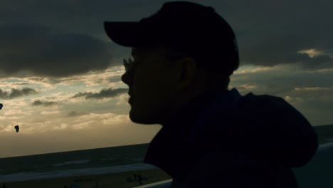 hombre con gorra camina hacia la playa de scheveningen durante la puesta de sol, en 1000 fps super slowmotion