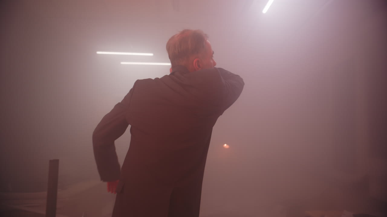 A man in a suit in a smoke-filled, chaotic room