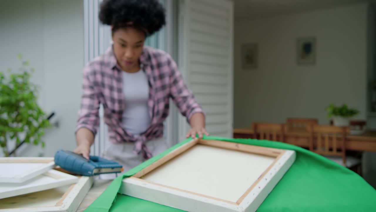 Per l'arredamento, una donna afroamericana fissa un tessuto verde sulla veranda con una pistola sparapunti elettrica blu.