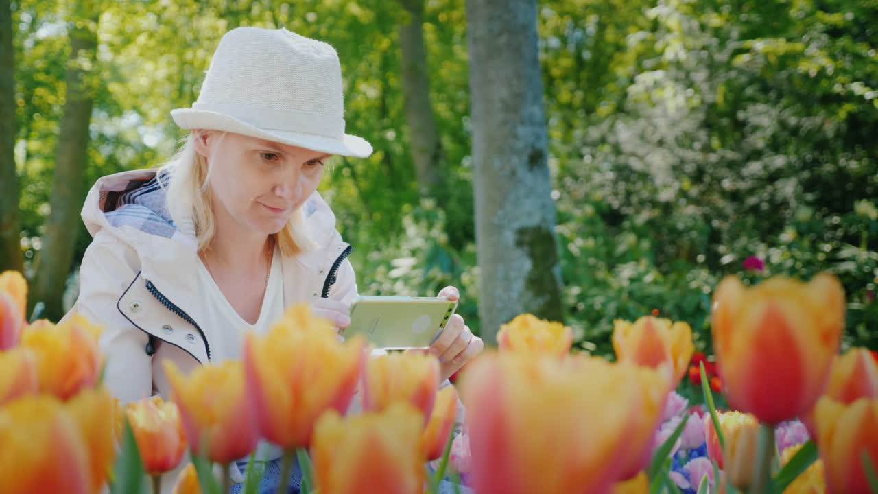 una chica con sombrero toma una foto de tulipanes