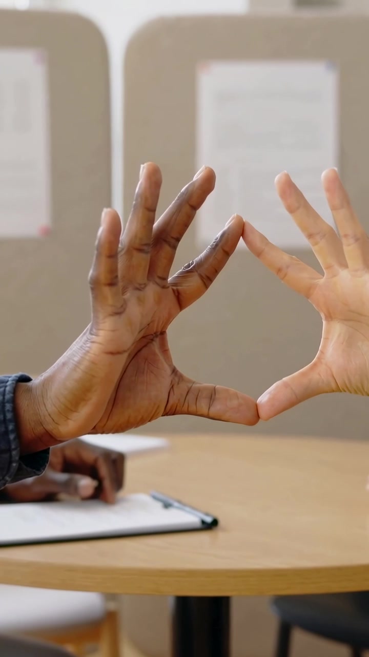 Video verticale: Avvicinandosi, un paio di mani che formano un cuore in un angolo per riunioni, denim, blocco appunti.
