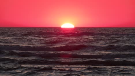 sun setting over the sea horizon with a long focal length, radiating in a golden glow. sunset over the sea horizon in 4k.