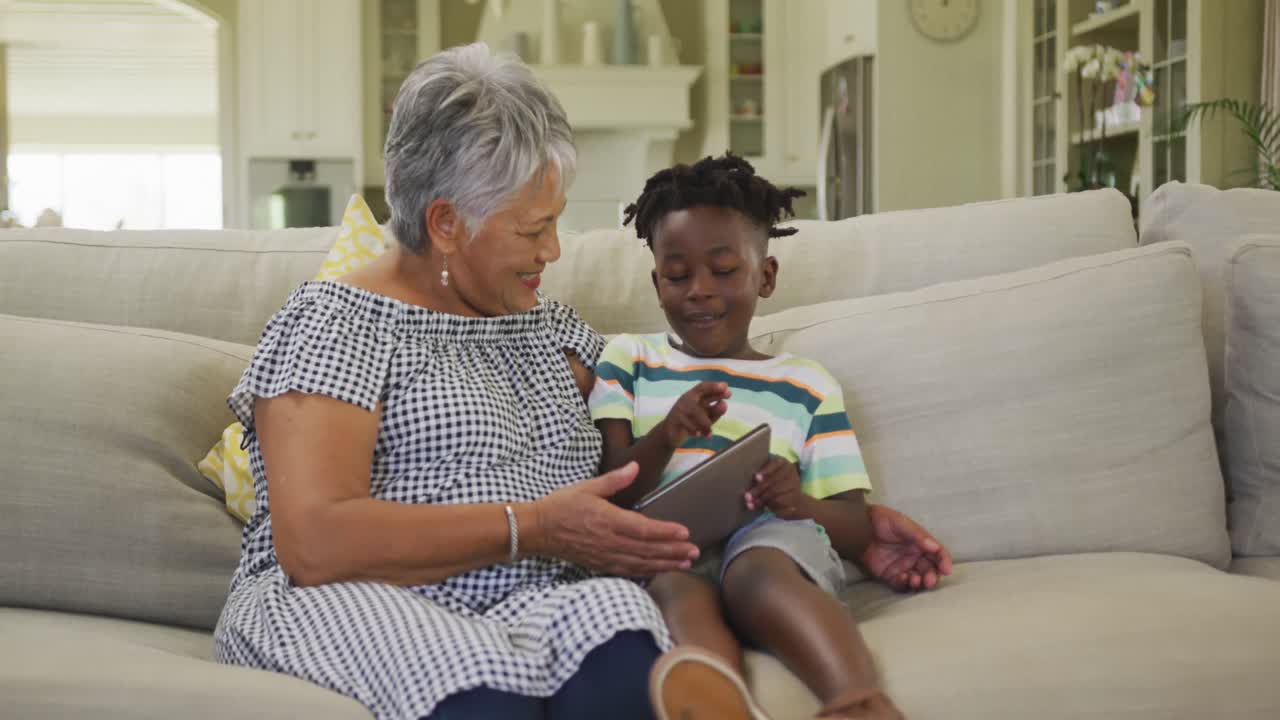 Grandmother and grandson using digital tablet at home