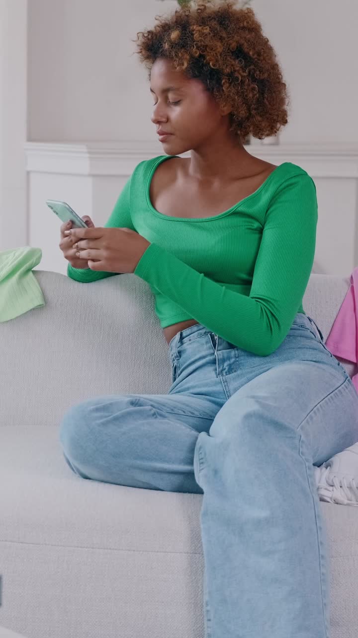 Young woman using smartphone checking messages beside delivery boxes and