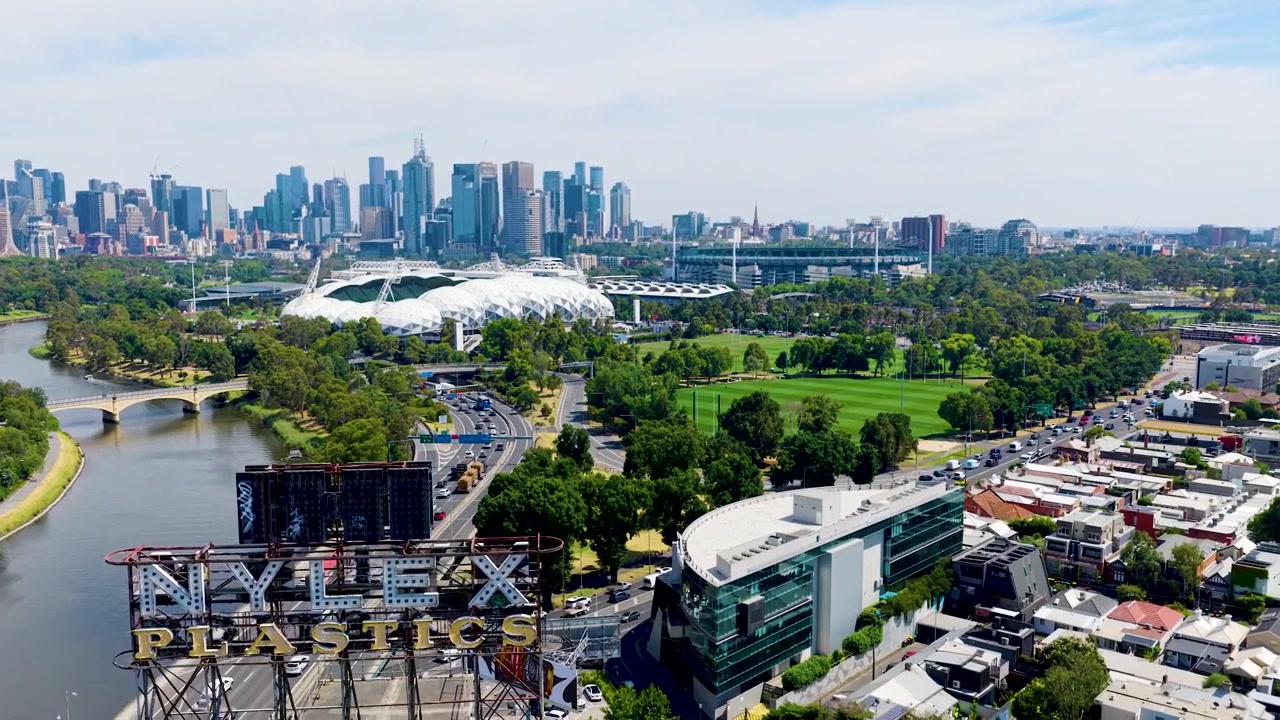 Filmatisk droneutsikt over Melbourne som viser Yarra-elven, Nylex Clock, AAMI Park, MCG, Collingwoods treningsfelt og CBD-skyline i ett ikonisk bypanorama