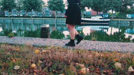 Lower-half-of-womans-body-in-dark-dress-with-bare-legs-walking-on-quay-side-shot