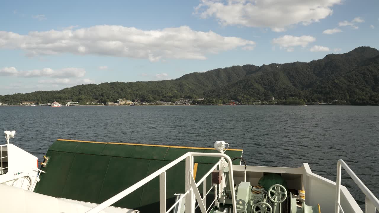 pov mirando sobre la barandilla del ferry en la proa delantera mientras navega hacia la isla de itsukushima