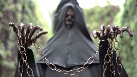 chained hands of a skeleton wearing a black tunic