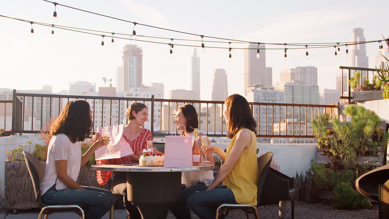 amigas celebrando su cumpleaños en la terraza de la azotea con el horizonte de la ciudad en el fondo