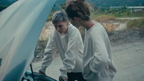 two women looking at a broken down car on the roadside