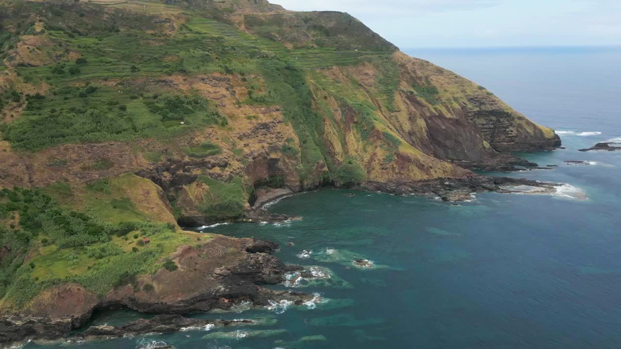 Panoramica aerea di scogliere verdi e aspre sull'oceano aperto a Santa Maria, Azzorre