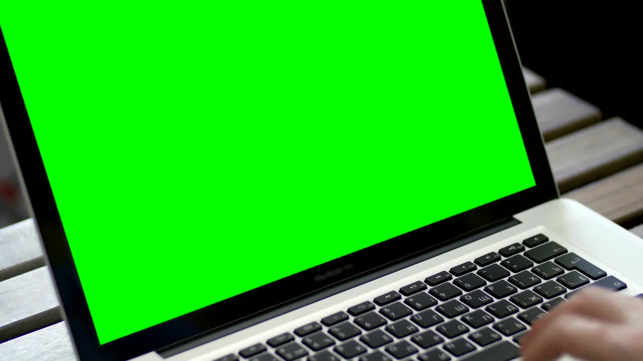 mano de un hombre trabajando en una computadora portátil escribiendo en el teclado. pantalla verde de cerca