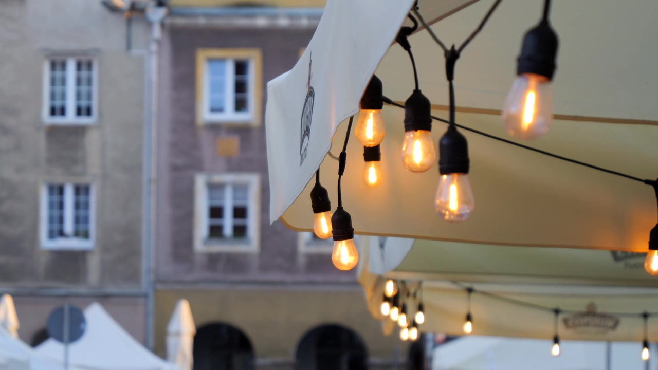Warm decorative string lights glow outside a restaurant in a historic old town creating an inviting evening atmosphere