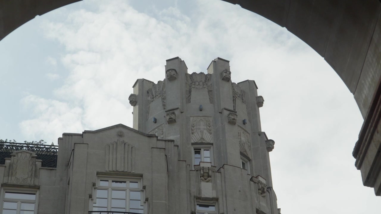 Dettaglio di un edificio storico in stile art déco con intricati particolari della facciata, visto attraverso un arco