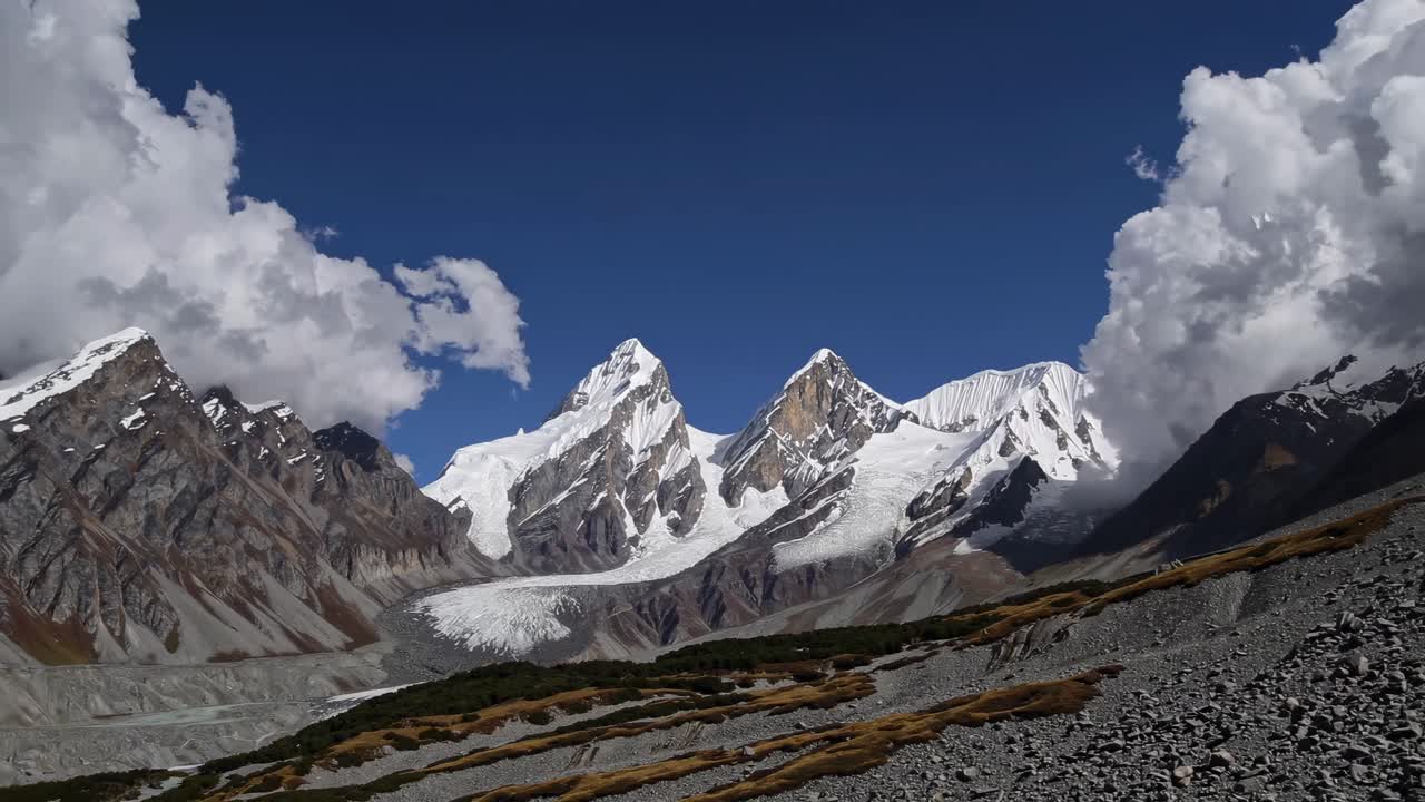 A stunning wide-angle video captures snow-capped mountains under a clear blue sky, framed