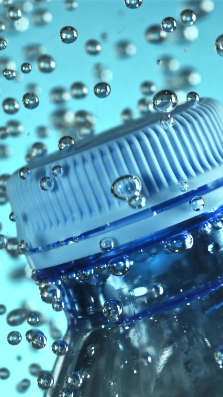 Bottiglia d'acqua di plastica immersa in acqua blu scintillante con bolle.