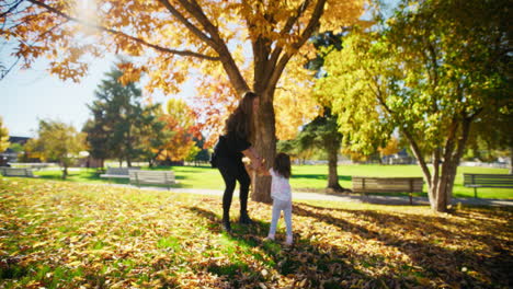 mother and daughter playing in autumn leaves