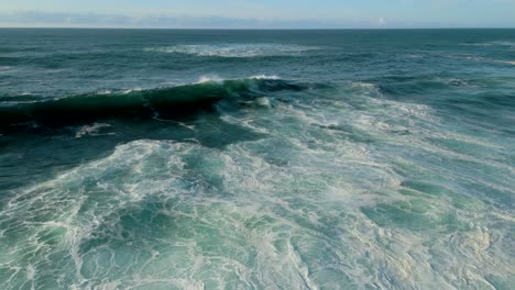 seascape with huge foamy waves rolling onto shoreline