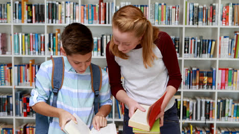 Estudiantes-Sonrientes-Leyendo-Un-Libro-En-La-Biblioteca