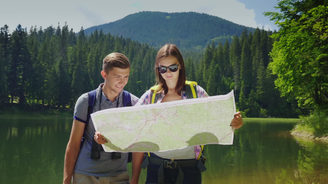 мужчина и женщина путешествуют вместе они ориентируются по карте мужчина смотрит в бинокль