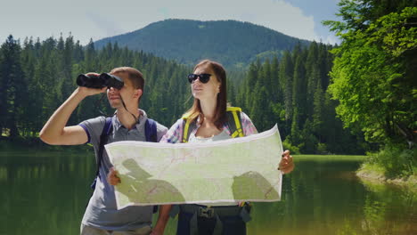 man and woman travelers together they orient themselves on the map the man looks through binoculars