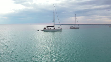 tourists on sailboats on the sea in platja des trenc, mallorca, spain