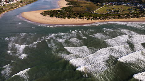 waves near goukou estuarine river mouth with view of still bay town