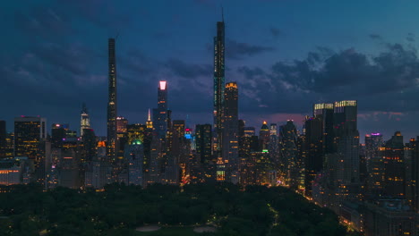 Day-transitions-to-night,-aerial-sliding-shoot-of-New-York-City-at-blue-hour,-with-avenues-crossing-the-city-from-one-side-to-another