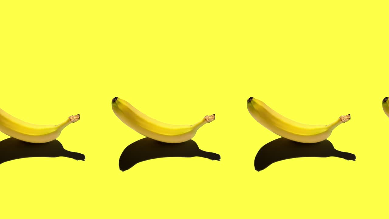 밝은 배경에 고립 된 익은 노란 바나나와 함께 원활한 루핑 애니메이션. 정오에 태양에서 단단한 그림자