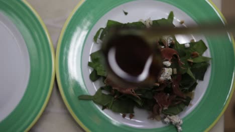 rising coming into focus shot of a salad being garnished with a dressing