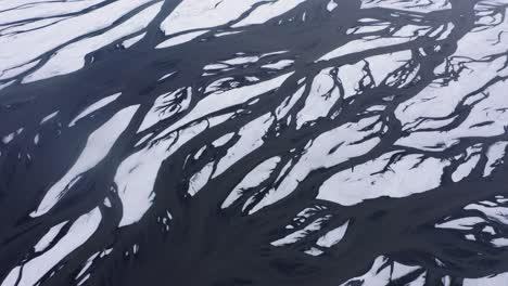 eldvatn glacial river delta in south iceland covered with ice and snow during daytime - aerial top down shot