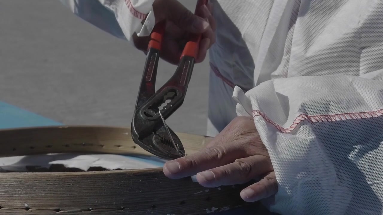 Close Up Of Boat Maker Using Pliers To String The Cockpit Of Kayak
