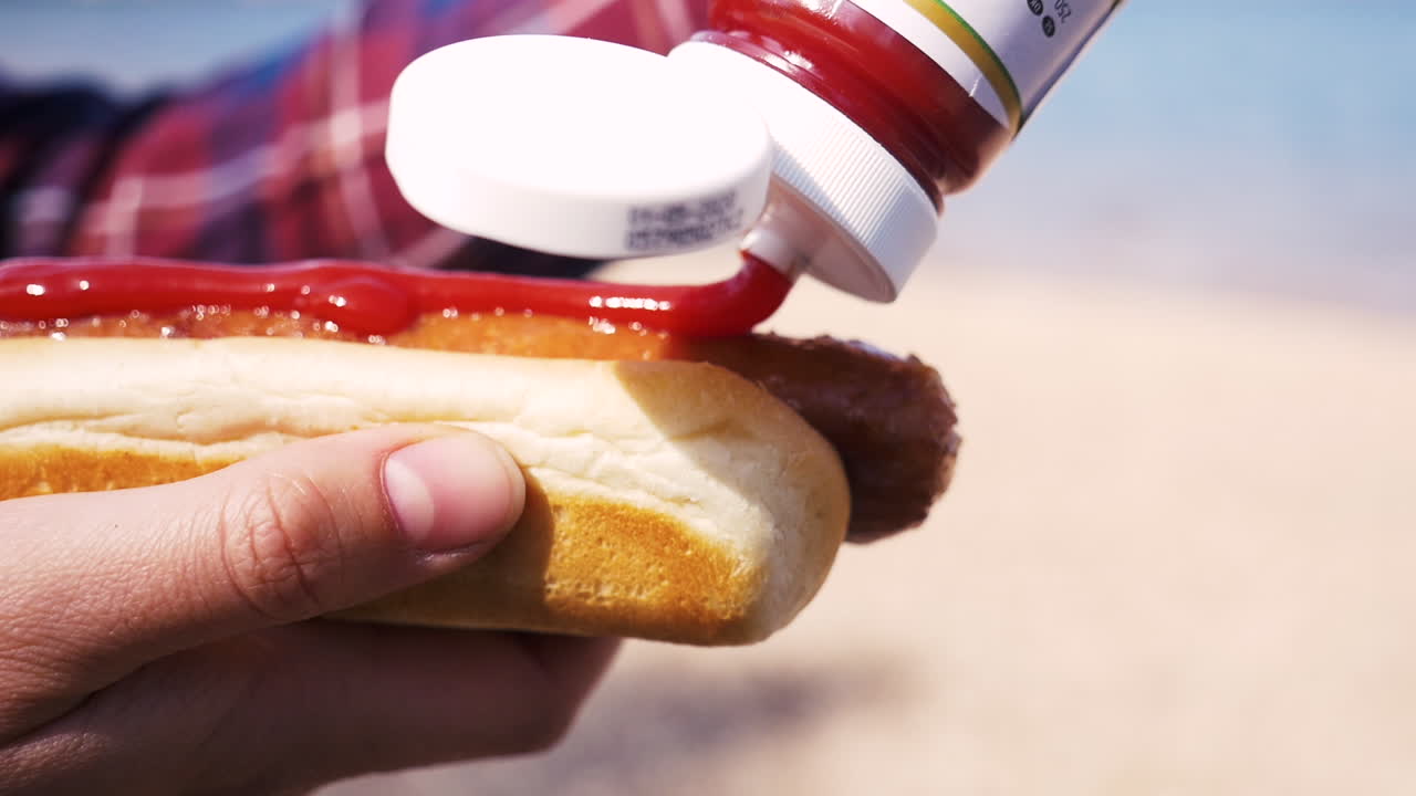 cerca de chica poniendo ketchup en una salchicha con pan en el lago
