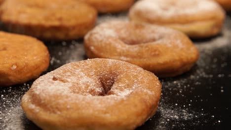 a sugar powder falls on a doughnuts on the black desk