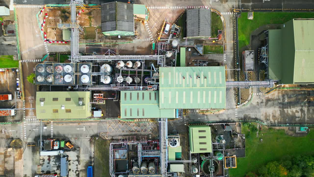 la vista aérea se centra en una planta química británica, mostrando tuberías, estructuras metálicas, torres de refrigeración y almacenamiento de productos químicos