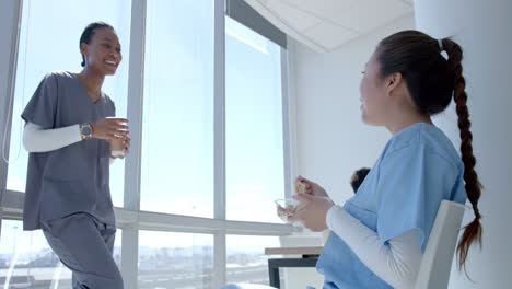 young african american healthcare worker and young asian healthcare worker enjoy a break in a bright