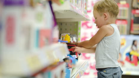 Niño-Jugando-Con-Un-Coche-De-Juguete-En-La-Tienda