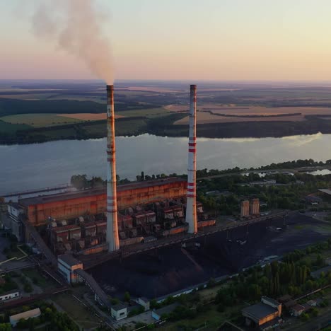 industrial enterprise on nature background. chemical plant with pipes near the river. dirty smoke pours into the air from factory. environmental pollution. aerial view