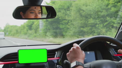 primer plano de una mujer conductor con manos libres unidad para pantalla verde teléfono móvil montado en el tablero de instrumentos