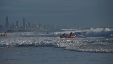 salvavidas voluntarios australianos en servicio - equipo salvavidas de surf montando olas ásperas en un bote de goma inflable - horizonte de la costa dorada desde la playa de currumbin, queensland, australia