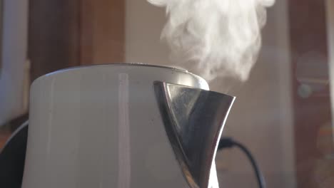 boiling water and steam comes out of white modern kettle