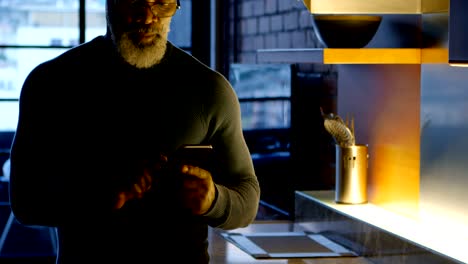 senior man using mobile phone in kitchen 4k