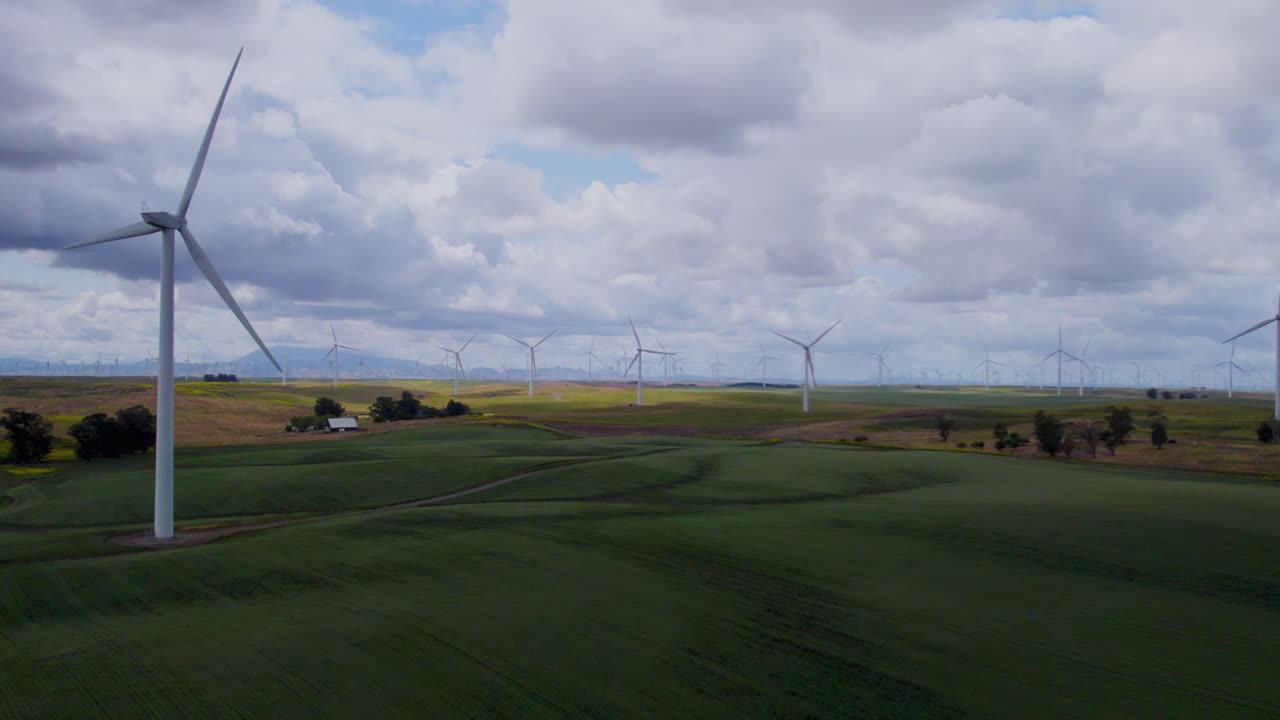 4k Slow motion aerial footage of windmills over agricultural land in california