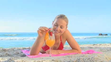 mujer bebiendo un cóctel en una playa