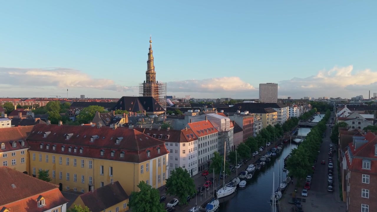 Filmato drone che sale sopra il canale di Christiania, svelando il paesaggio urbano di Copenaghen con l'iconico campanile a spirale della Chiesa del Nostro Salvatore (Vor Frelsers Kirke) sullo sfondo.