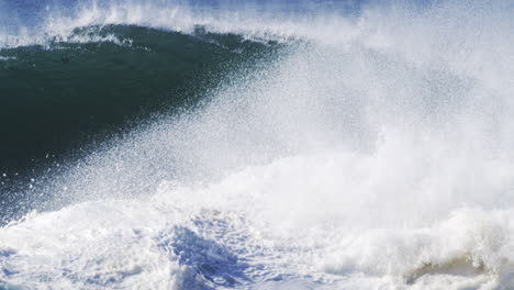 towering white wave crashes with textured mist lifting above in super slow motion