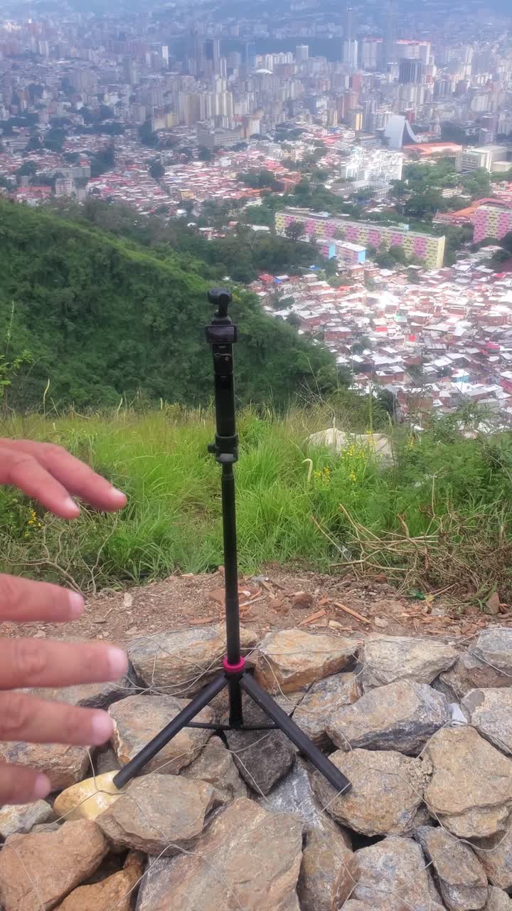 bald man uses a handheld camera to document the sharp economic disparity visible across the Caracas valley