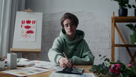 une femme artiste peint des fleurs dans son studio.