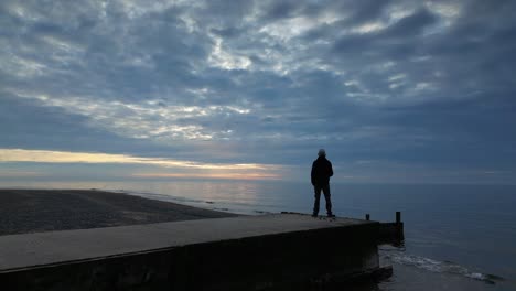 aproximação em câmera lenta ao homem que estava no cais ao pôr do sol na praia de fleetwood, lancashire, reino unido.