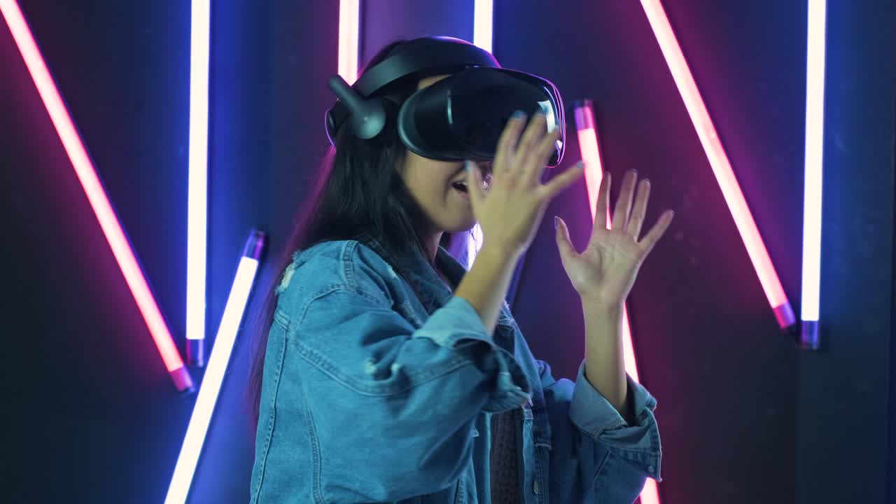 giovane donna che gioca e sorride nell'auricolare vr. casco di realtà virtuale sullo sfondo di illuminazione a colori